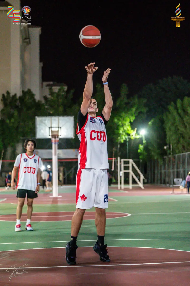 A basketball player rising for a shot under the lights